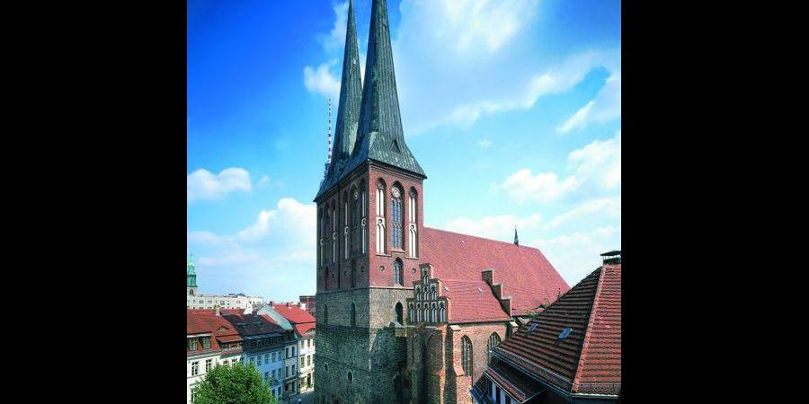 Die Nikolaikirche mit ihrem Turmsockel aus grauen Feldsteinen und den Zwillingstürmen aus rotem Backstein mit grünen Turmspitzen.