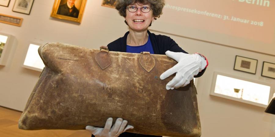 Foto von Sammlungsbetreuerin Bärbel Reißmann mit Reisetasche von Max Reinhardt