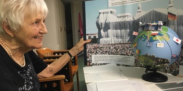 Ältere Frau schaut auf einen selbstgestalteten Globus