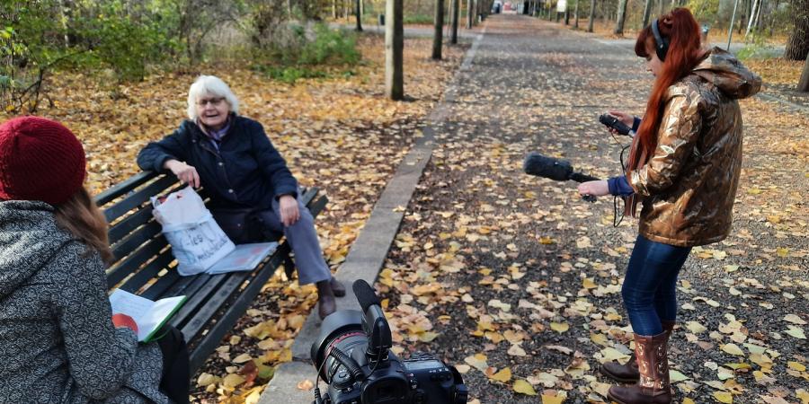 Frau auf einer Bank sitzend wird interviewt