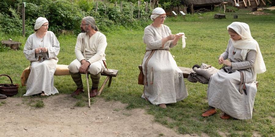 Eine Gruppe mittelalterlich gekleideter Menschen im Museumsdorf Düppel