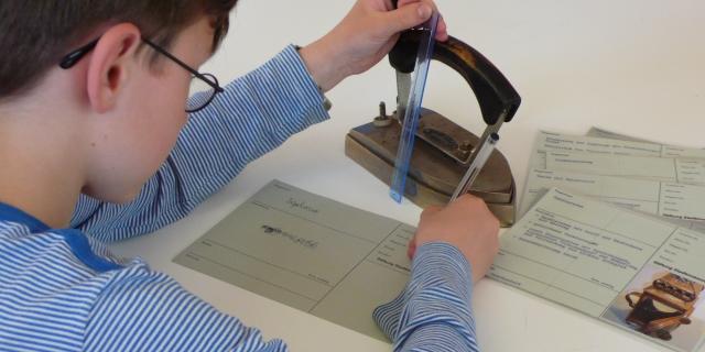 Ein Schüler beim Untersuchen und Dokumentieren von Objekten