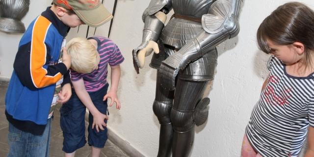 Kinder untersuchen eine Ritterrüstung in der Waffenhalle