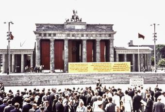Das mit Fahnen verhängte Brandenburger Tor und die Tafel mit einem Apell der DDR-Regierung an Kennedy, 26.6.1963