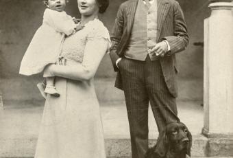 Familienportrait, Frau hält Sohn auf dem Arm, Mann steht daneben mit Hund