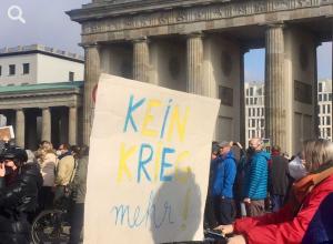 Demonstrierende mit Plakat "Kein Krieg mehr" vor dem Brandenburger Tor