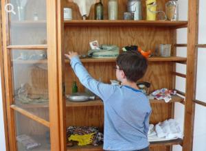 Ein Schüler nimmt vorsichtig ein historisches Objekt aus einem Schrank