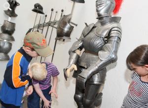 Kinder bestaunen eine Ritterrüstung in der Waffenhalle des Märkisches Museums © Stadtmuseum Berlin | Foto: Michael Setzpfandt