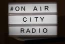 Leuchttafel mit dem Schriftzug # on air City Radio
