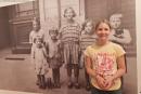 Ein Mädchen steht vor einem alten Foto, das Kinder zeigt